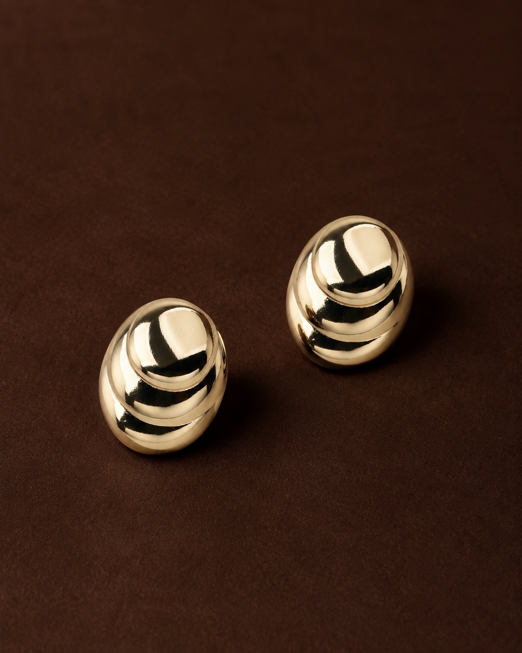 Pair of gold earrings on a brown background