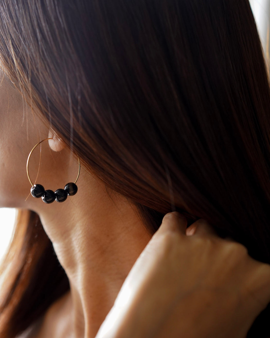Model wearing Nova gold beaded hoop earrings with mid-length hair