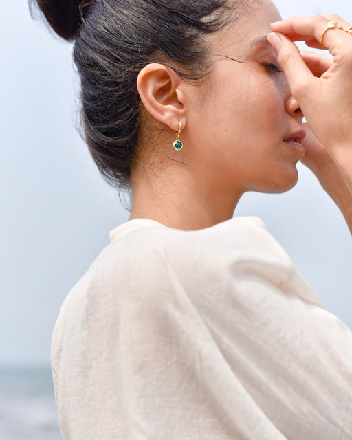 Woman wearing April gold hoop earrings 